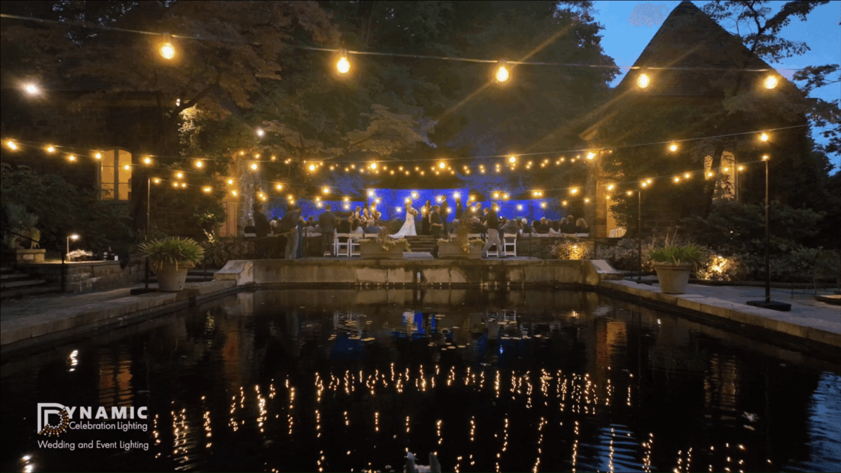 Wedding reception at night with string lights reflected over a pond
